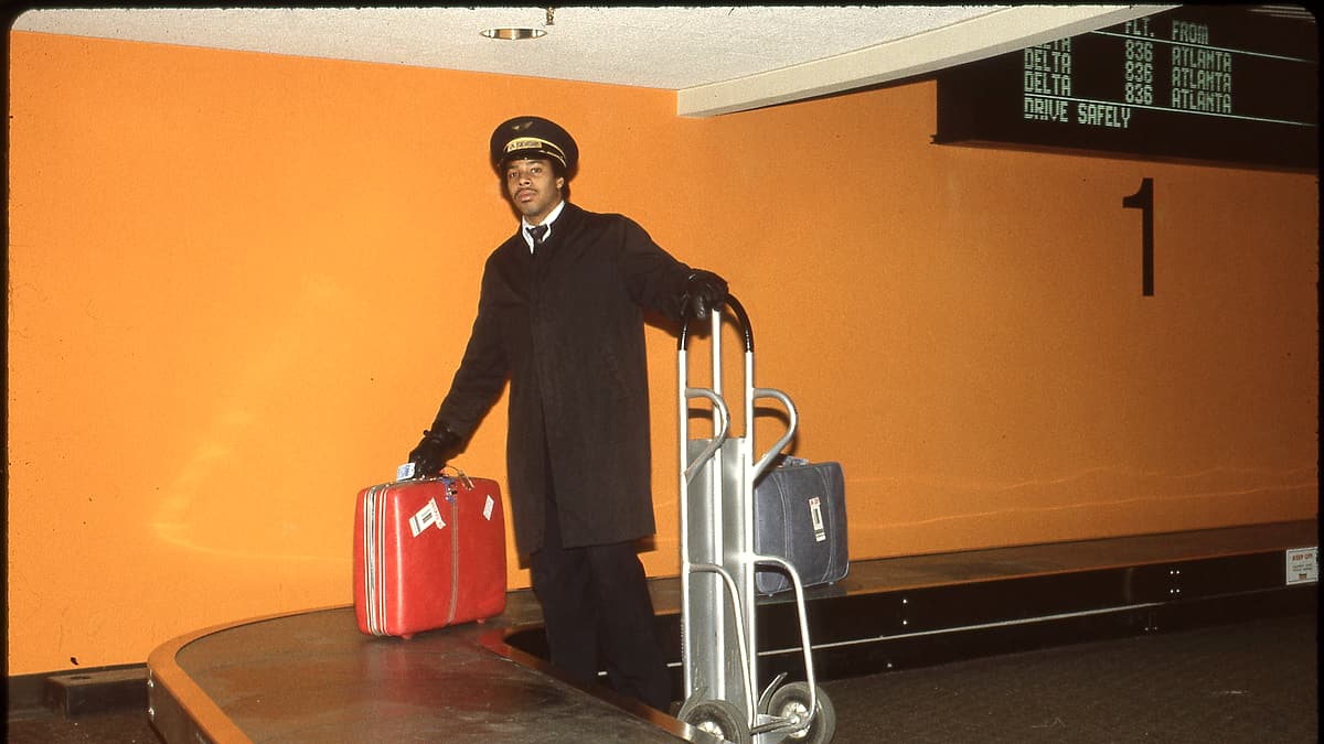 An unidentified airport employee, a Skycap porter, is seen by a baggage carousel