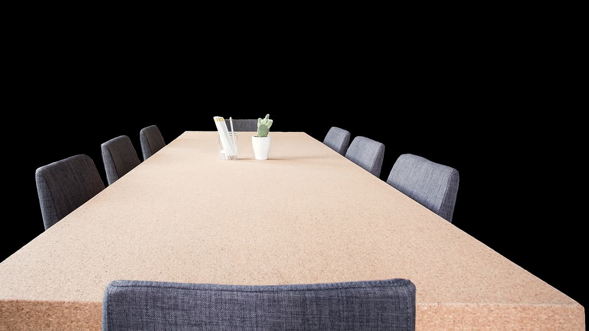 An empty meeting table with chairs drawn up around it, ready for a negotiation that has not begun